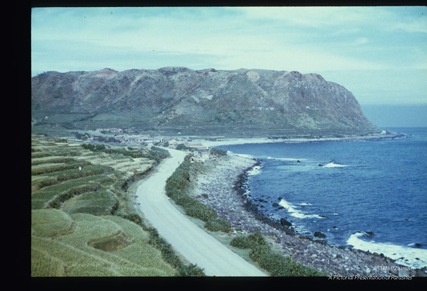 Village of Ali-lao at the northern tip of the island. The valley opens into the South China Sea. A road runs around the periphery of the island.